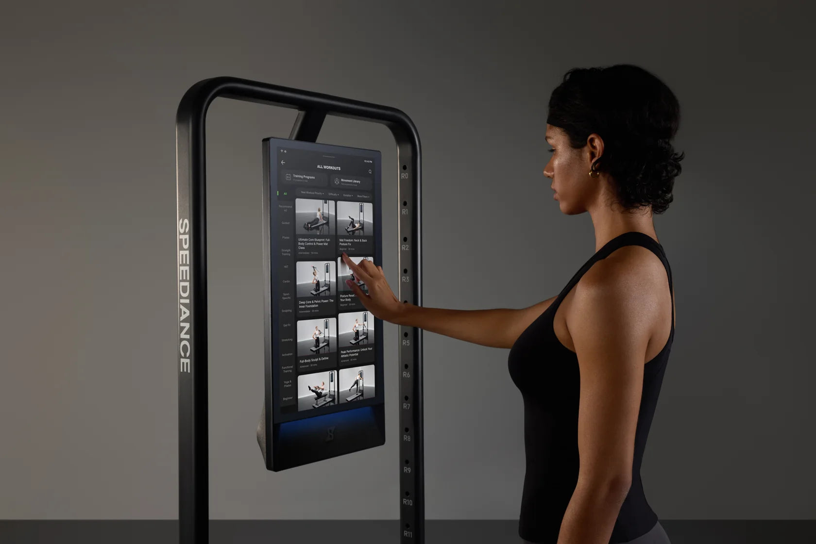 Een vrouw kiest een workout op het touchscreen van Gym Monster 3