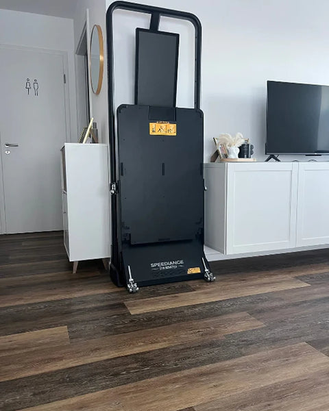 A Gym Monster folded upright in a living room beside a TV unit
