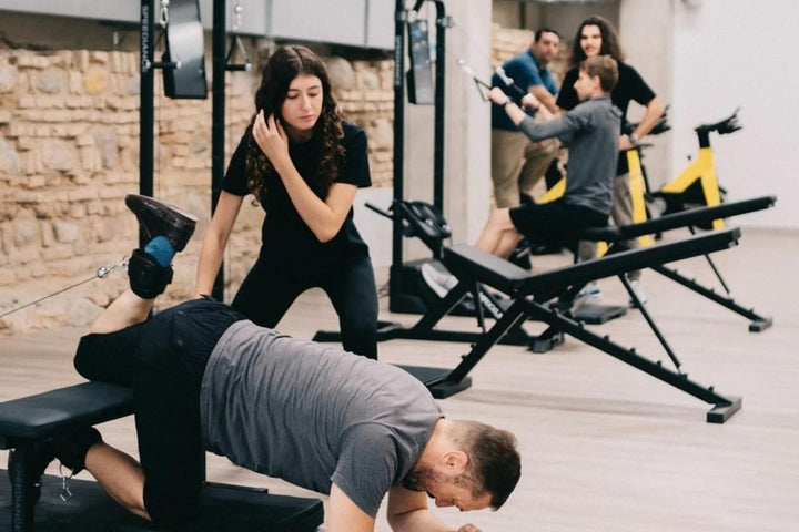 Een trainer coacht een klant in een studio met stenen wanden