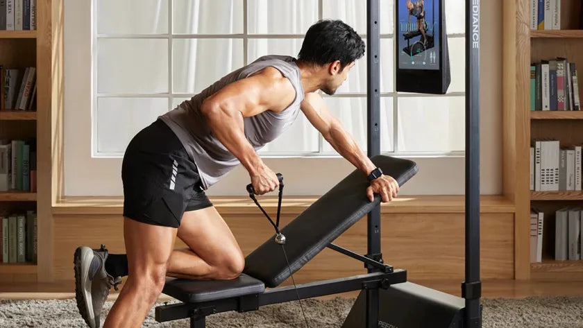 Een man traint thuis op Gym Monster 3 in een lichte, met boeken gevulde woonkamer