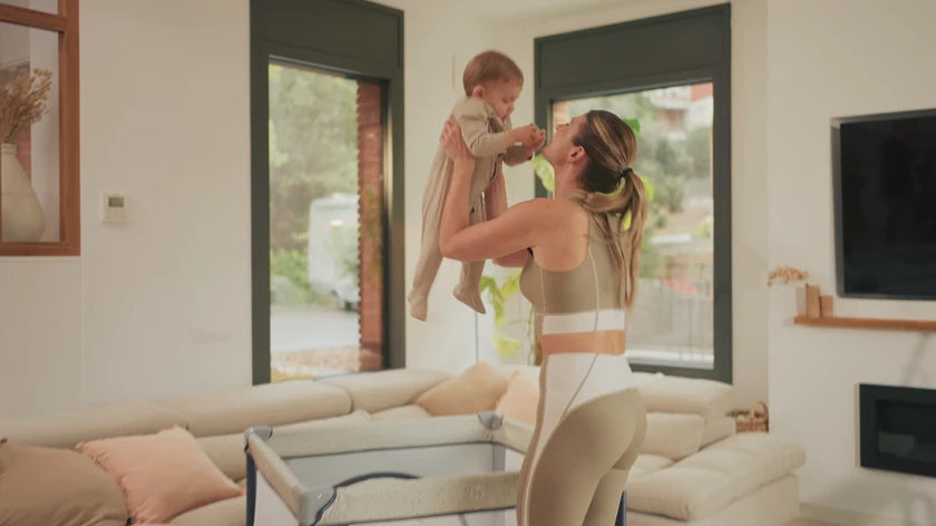 Een moeder tilt haar baby op in de woonkamer, thuis